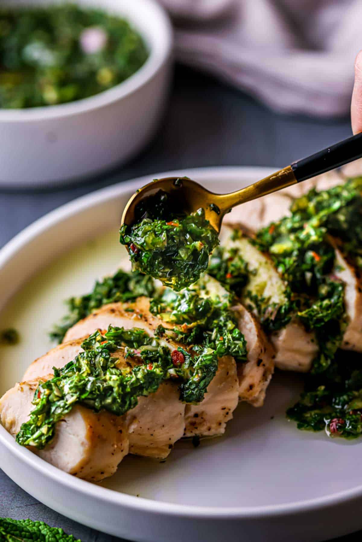 green sauce being spooned over pieces of chicken
