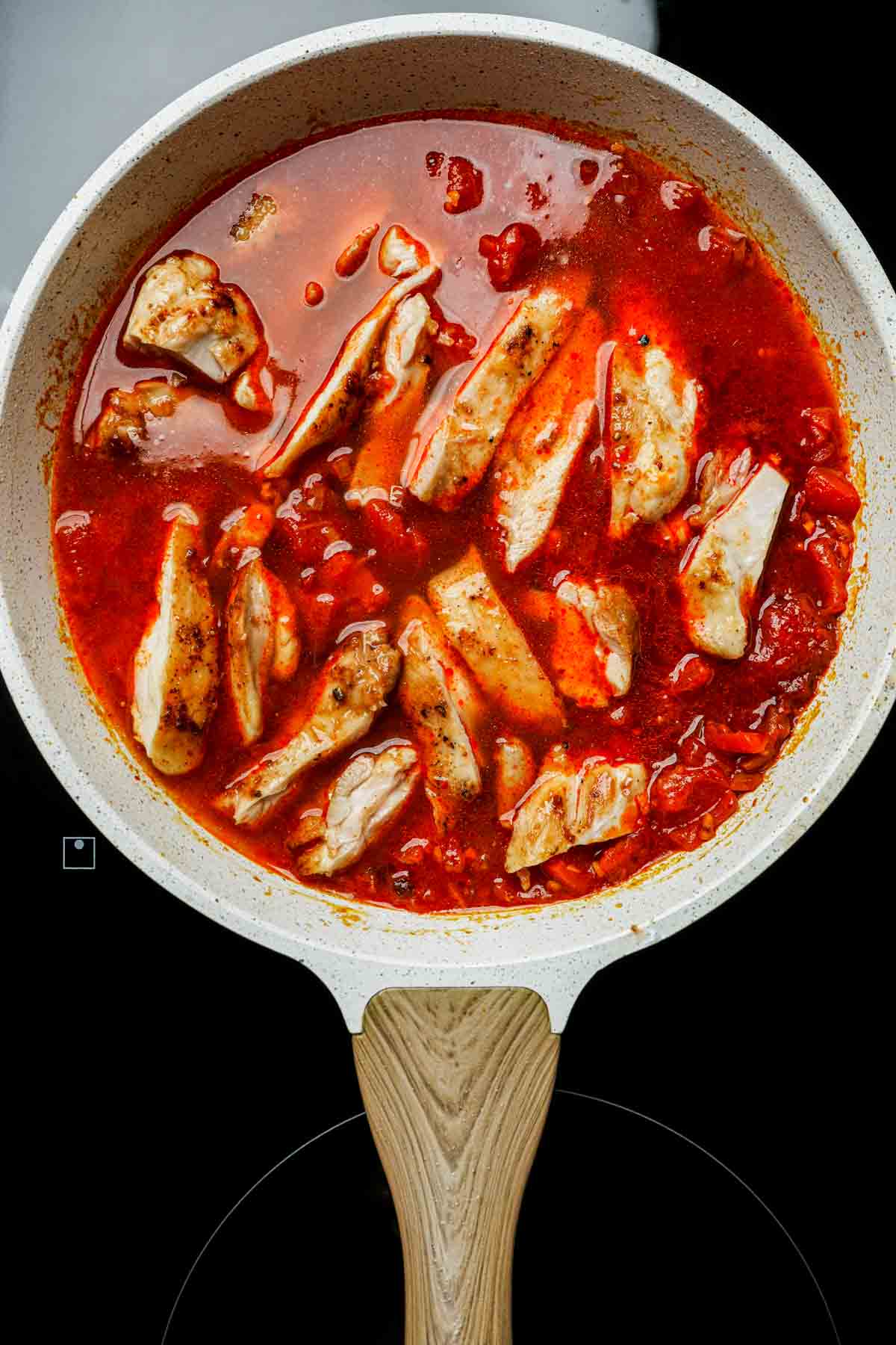 chicken slices in a red sauce in a skillet