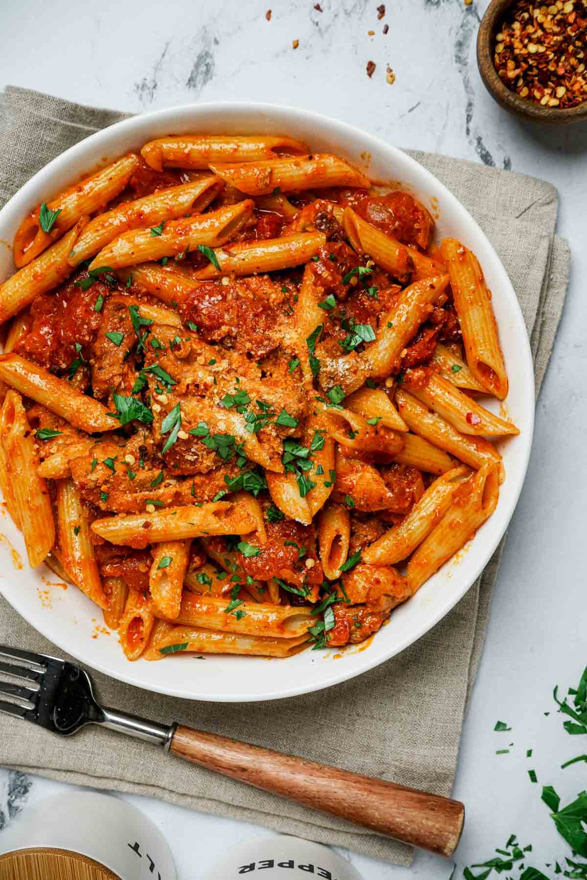 a bowl of pasta in red sauce garnished with green herbs
