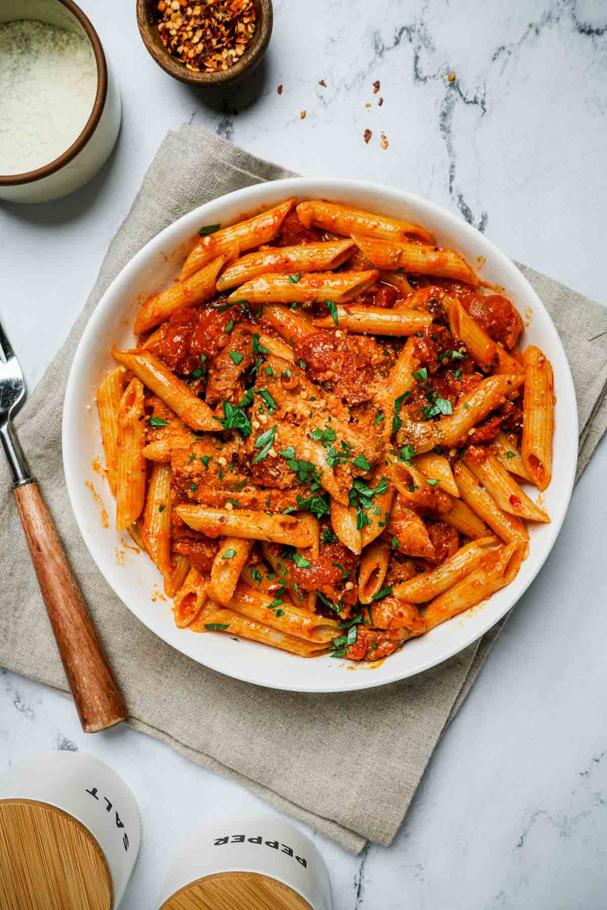a bowl of penne pasta in red sauce with fork on the side