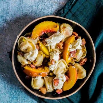 tortellini salad with peaches, pistachios, and ricotta cheese on top