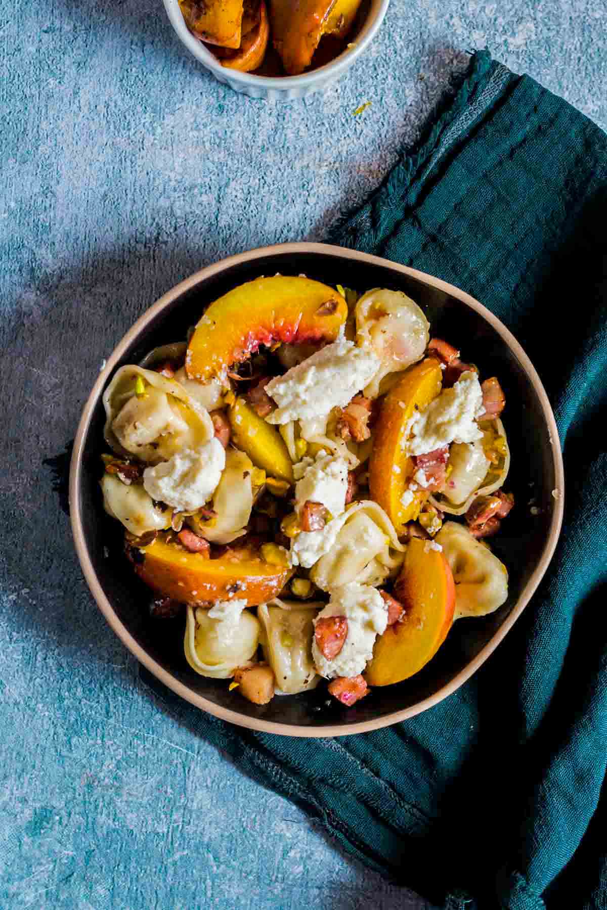 tortellini salad with peaches, pistachios, and ricotta cheese on top