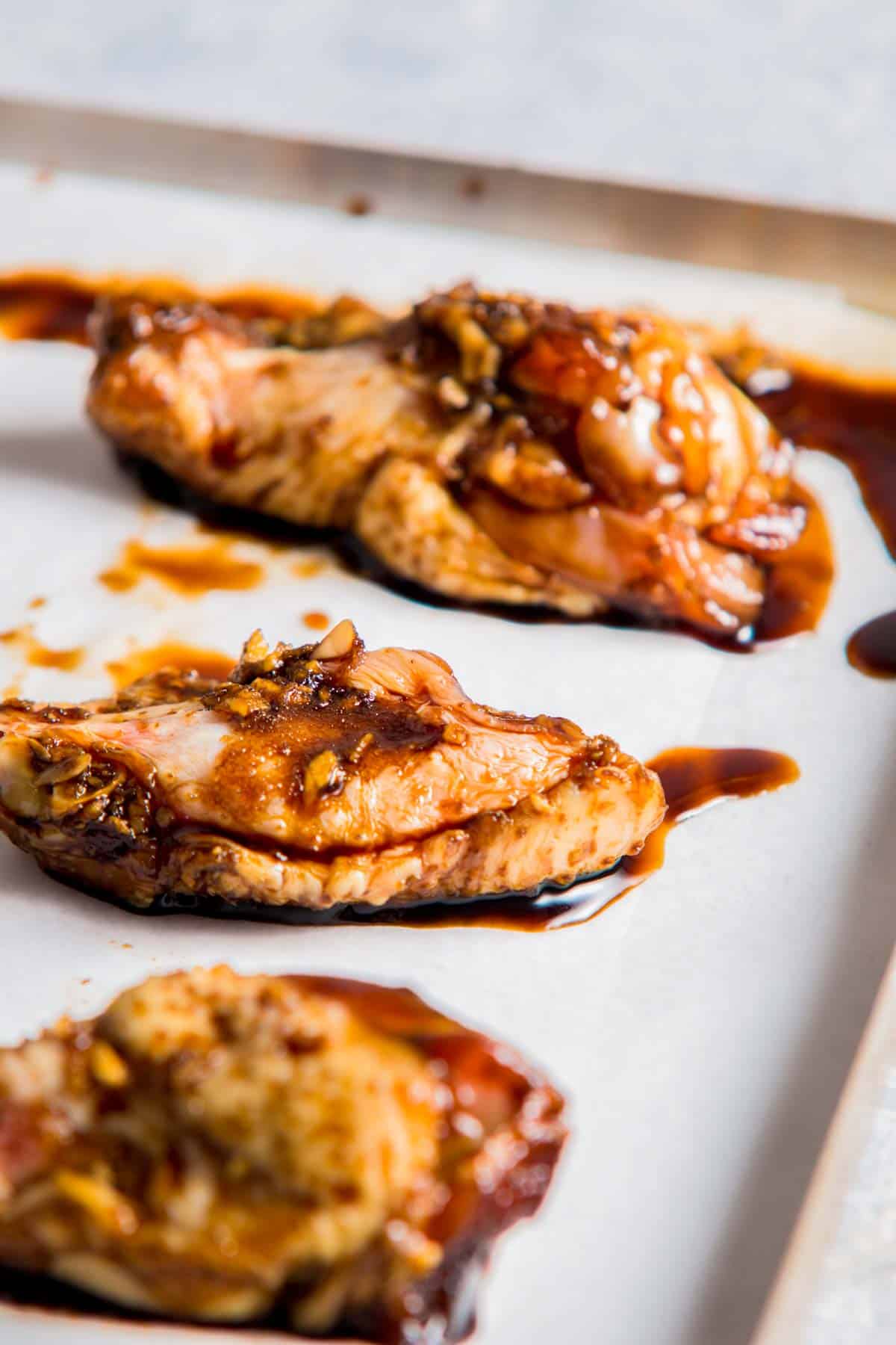 chicken wings in a brown sauce on a baking sheet