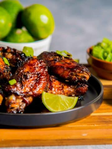 a plate of caramelized chicken wings with limes