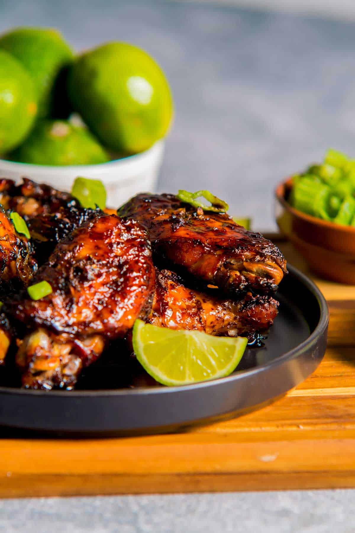 a plate of caramelized chicken wings with limes