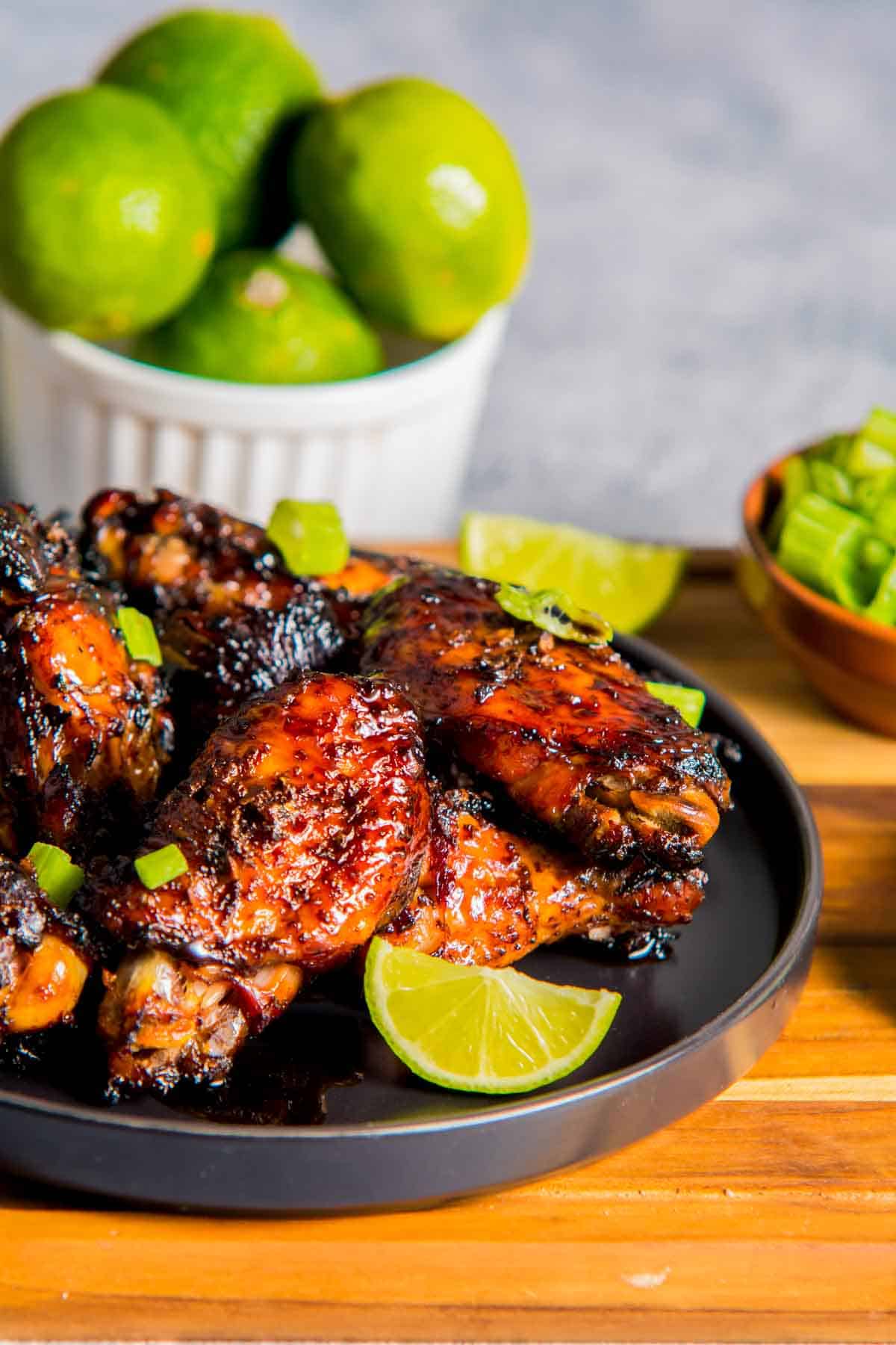 chicken wings on a plate with limes on the side