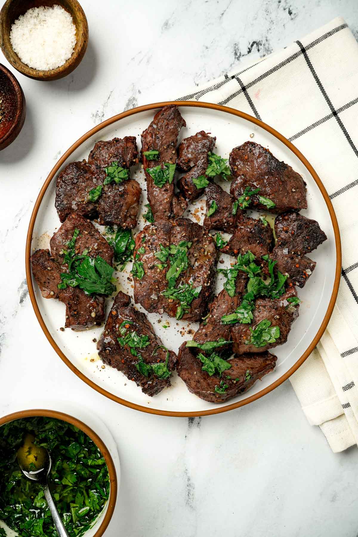 Slices of beef heart on a plate with green herbs