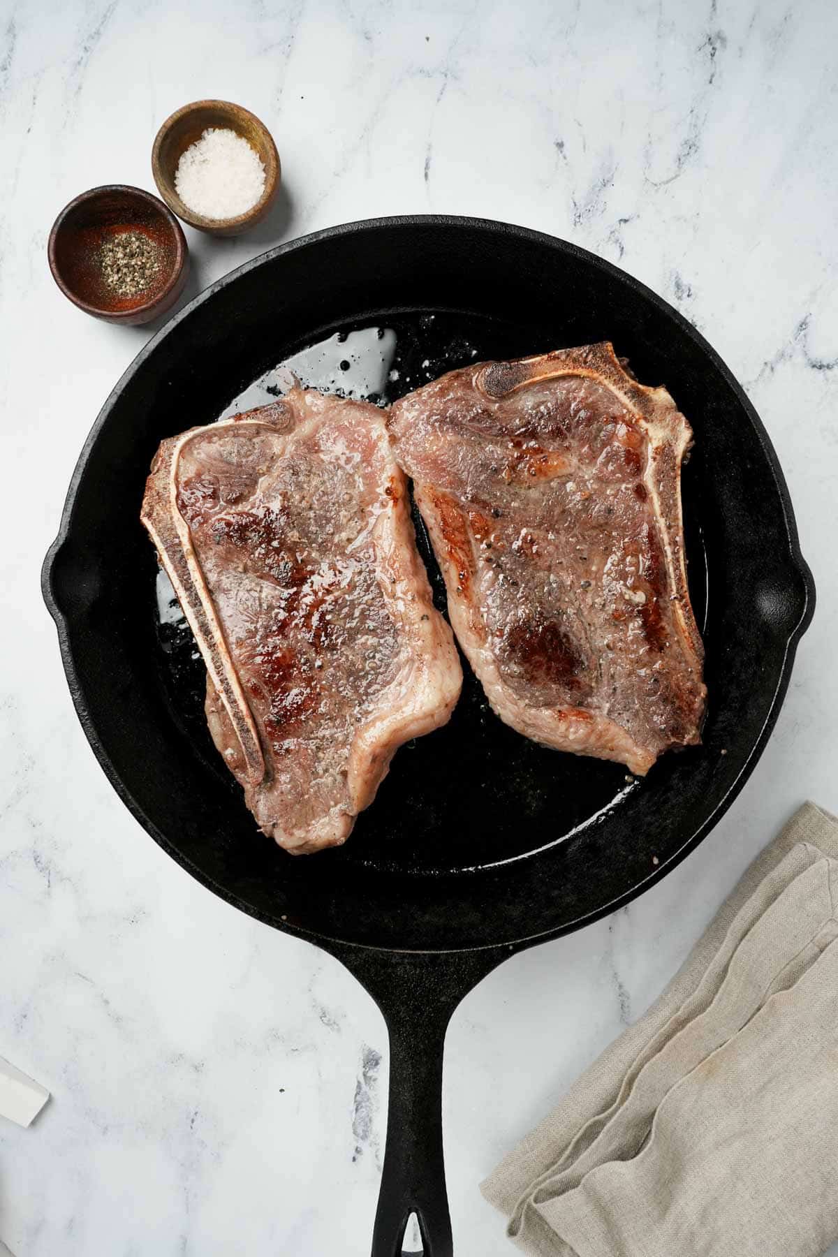 2 steak being brown in a cast iron skillet