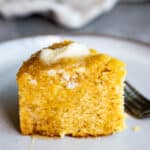 Side view of a piece of cornbread with butter and honey drizzled on top