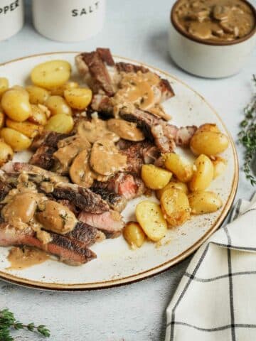 a plate of steak and potatoes smothered in brown mushroom gravy