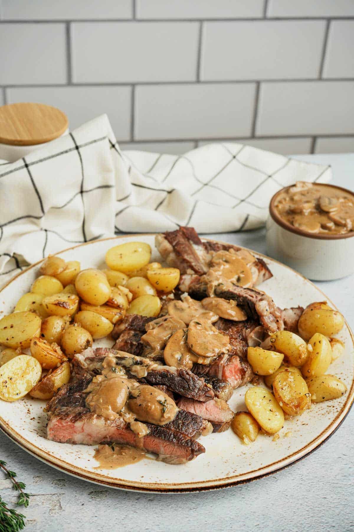 potatoes and sliced beef with gravy on a plate with a white towel in the background