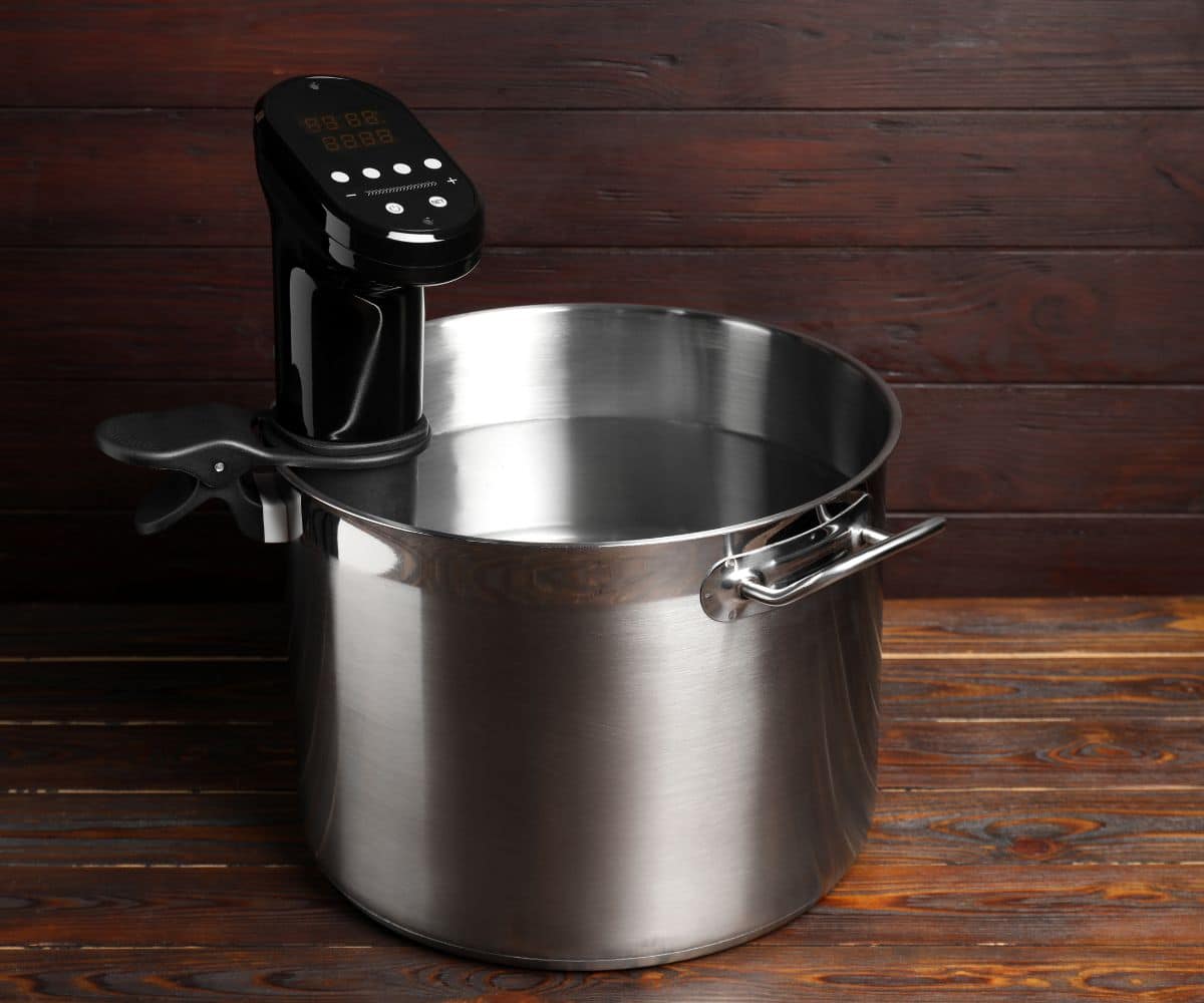 a stock pot with an immersion circulator in it against wood background