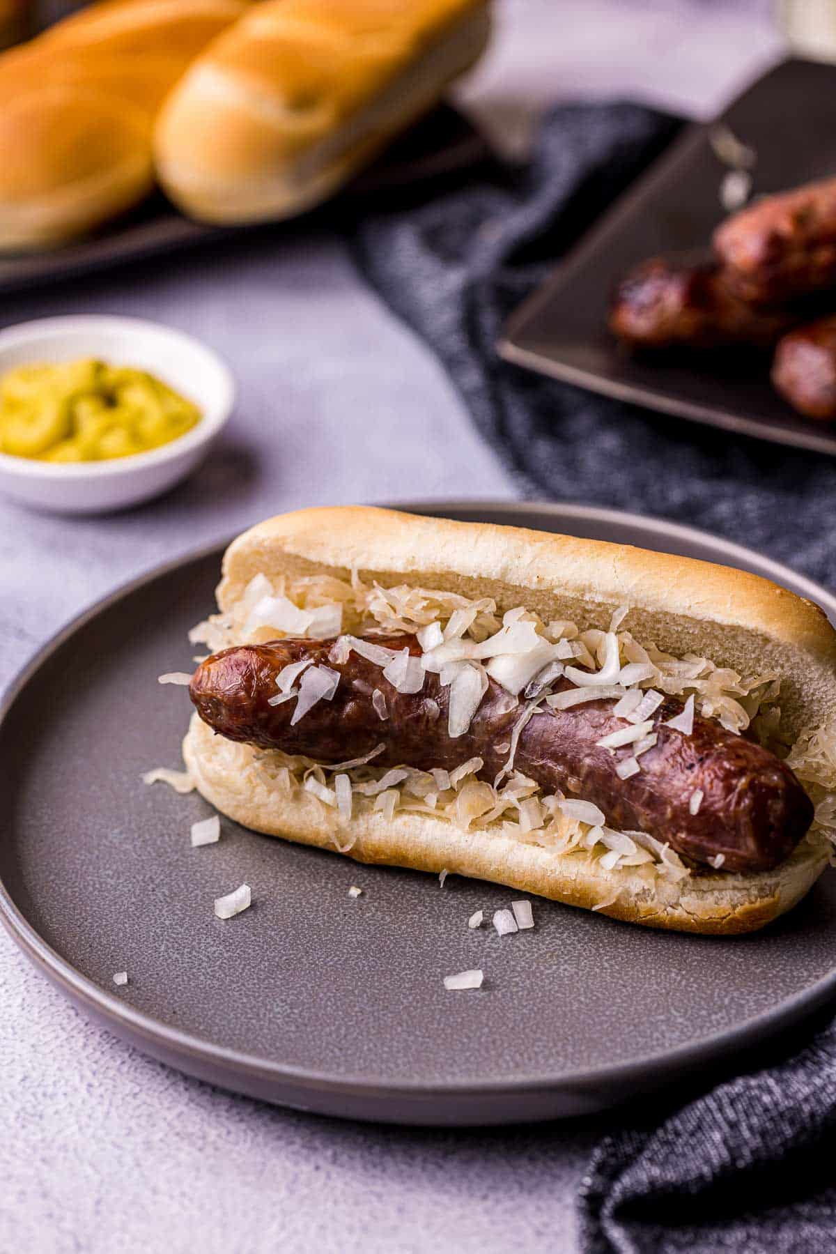 a sausage in a bun on a plate with diced onions
