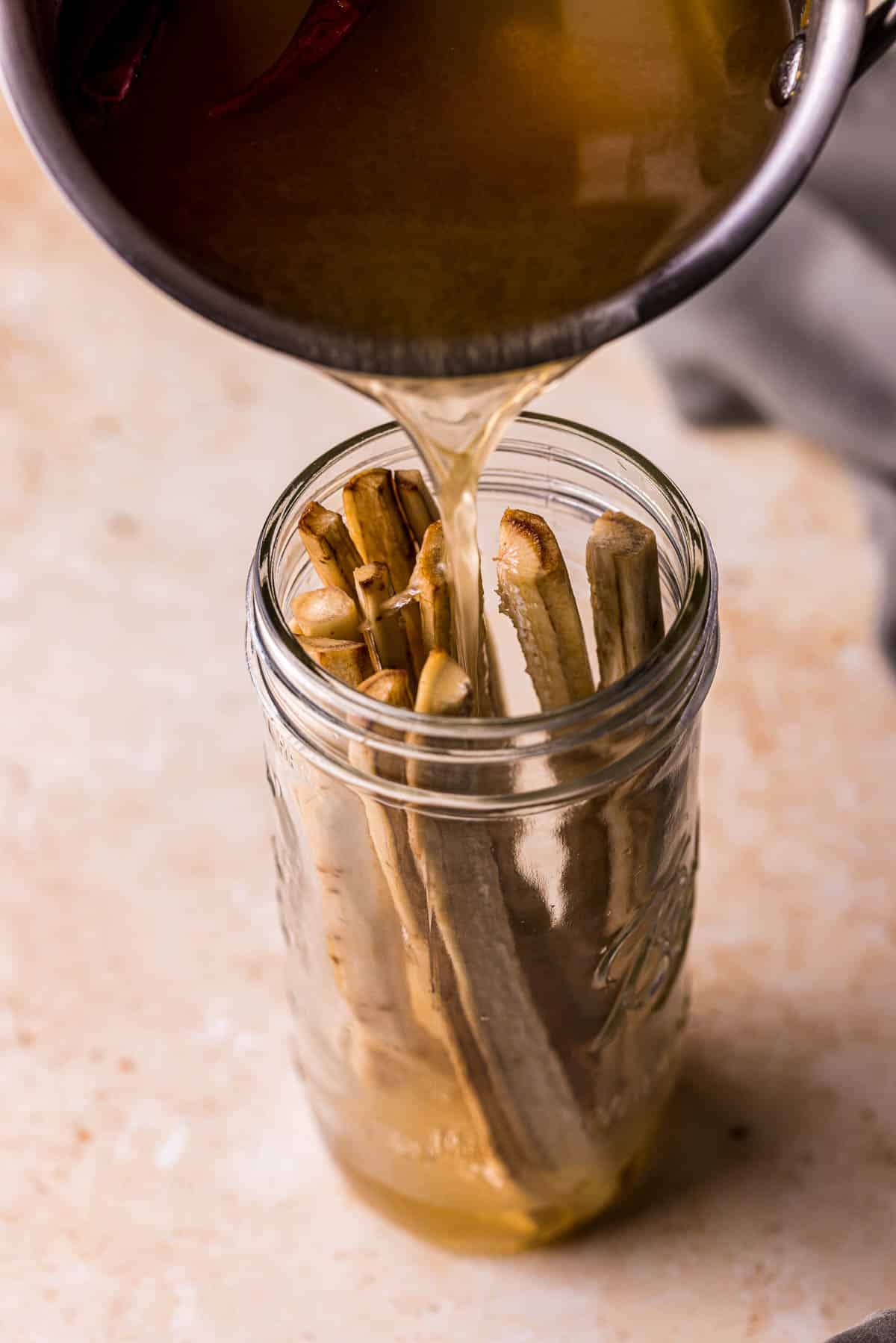 liquid being poured into a jar of white matchstick vegetables