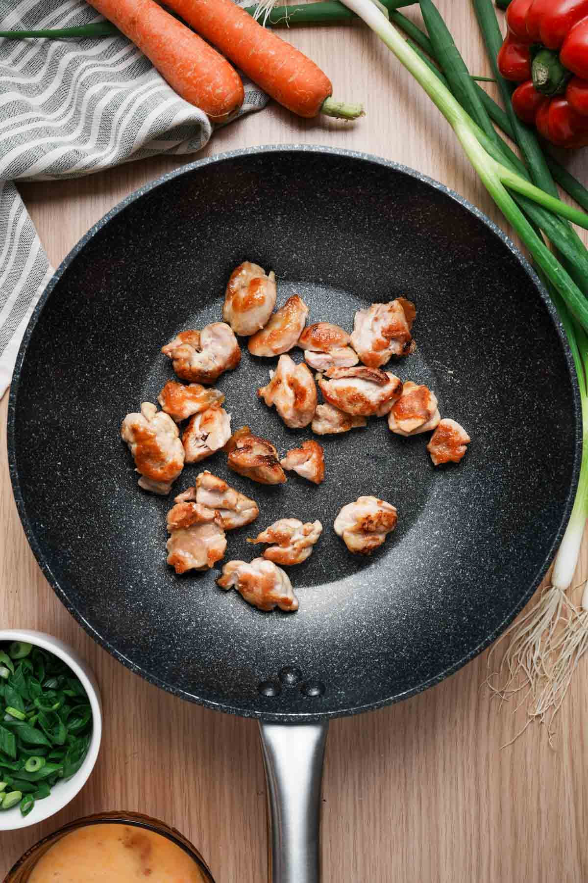 pieces of chicken cooking in a skillet