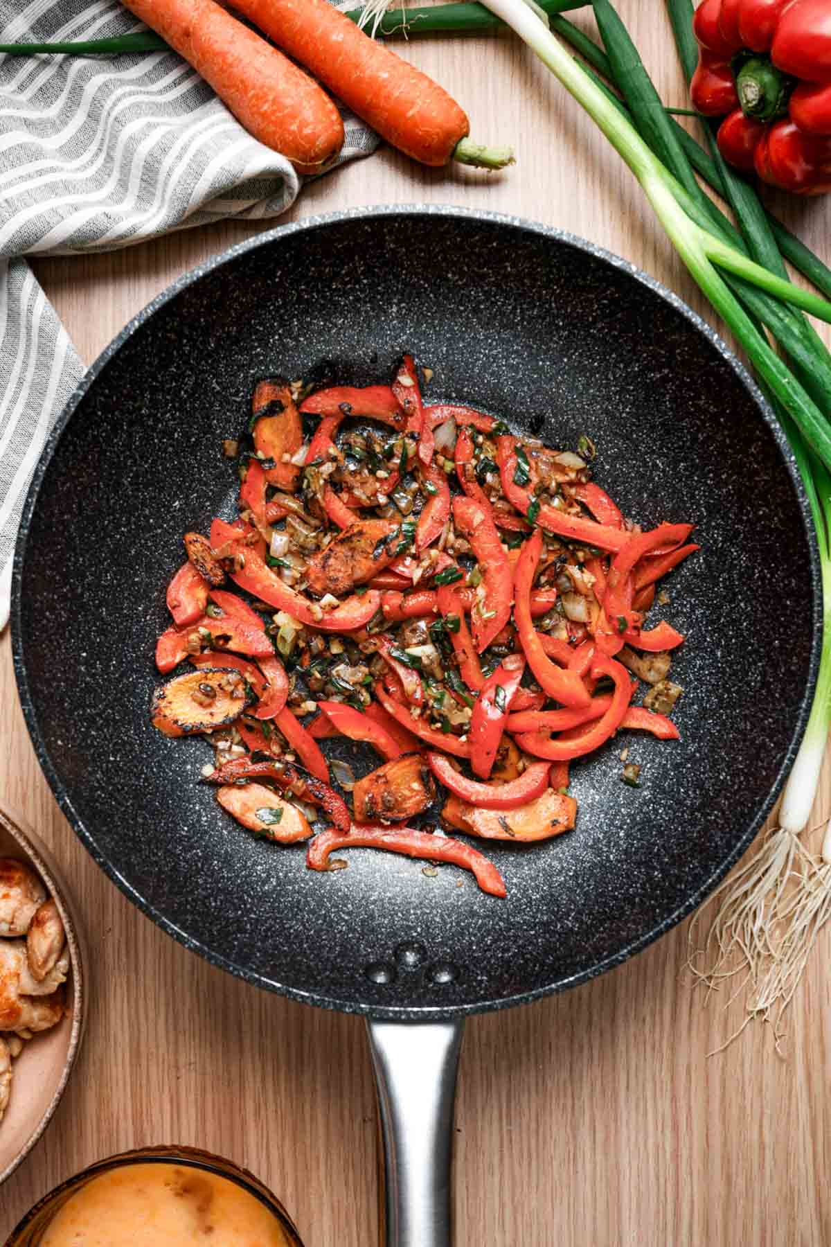 red peppers and vegetables cooking in a skillet