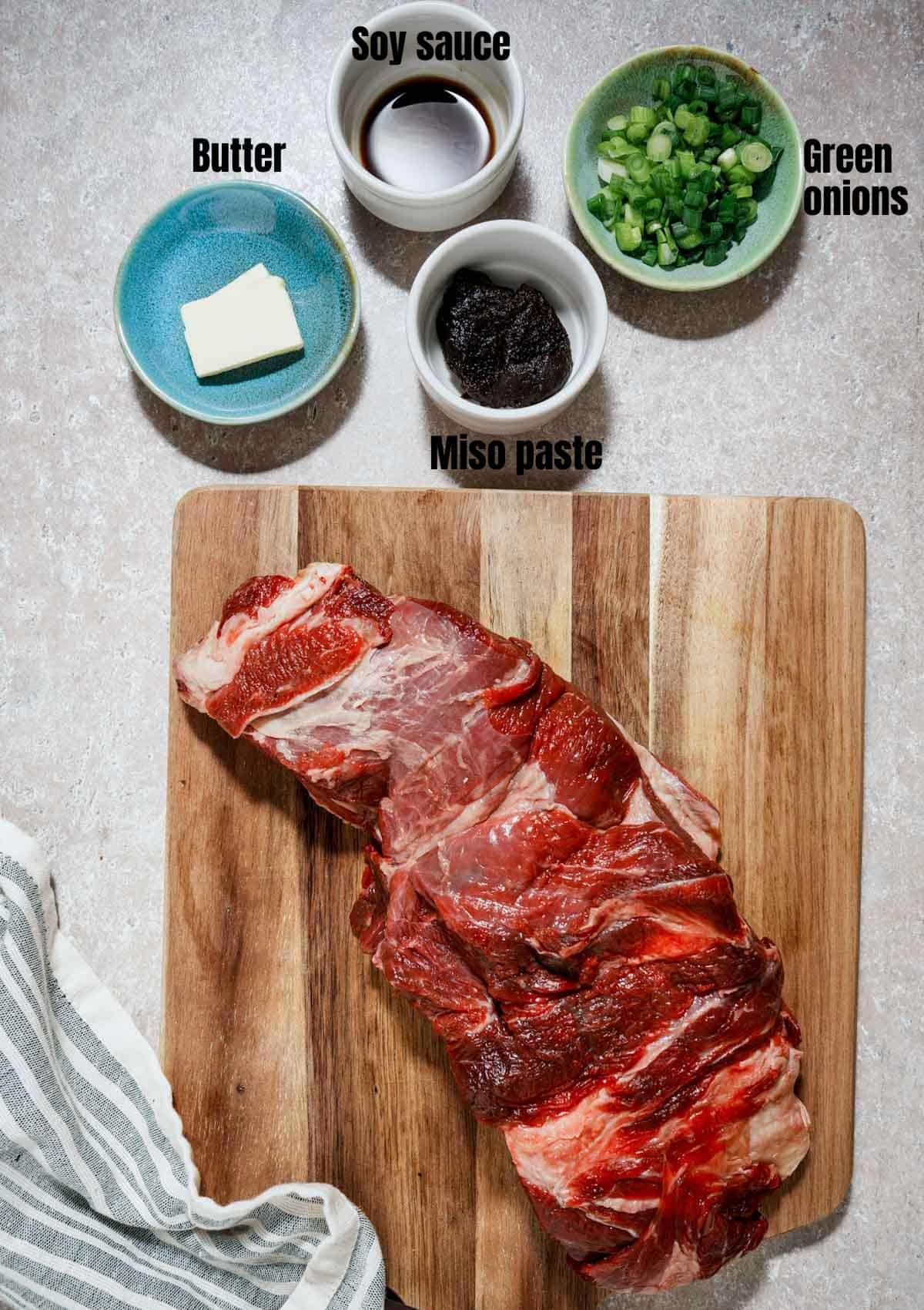 raw beef on a cutting board with bowls of seasonings on the side with text overlay