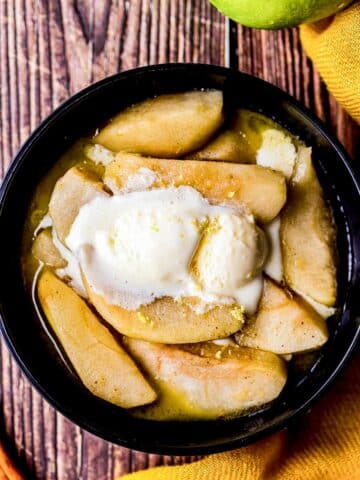 cooked apples slices in a bowl with ice cream on top