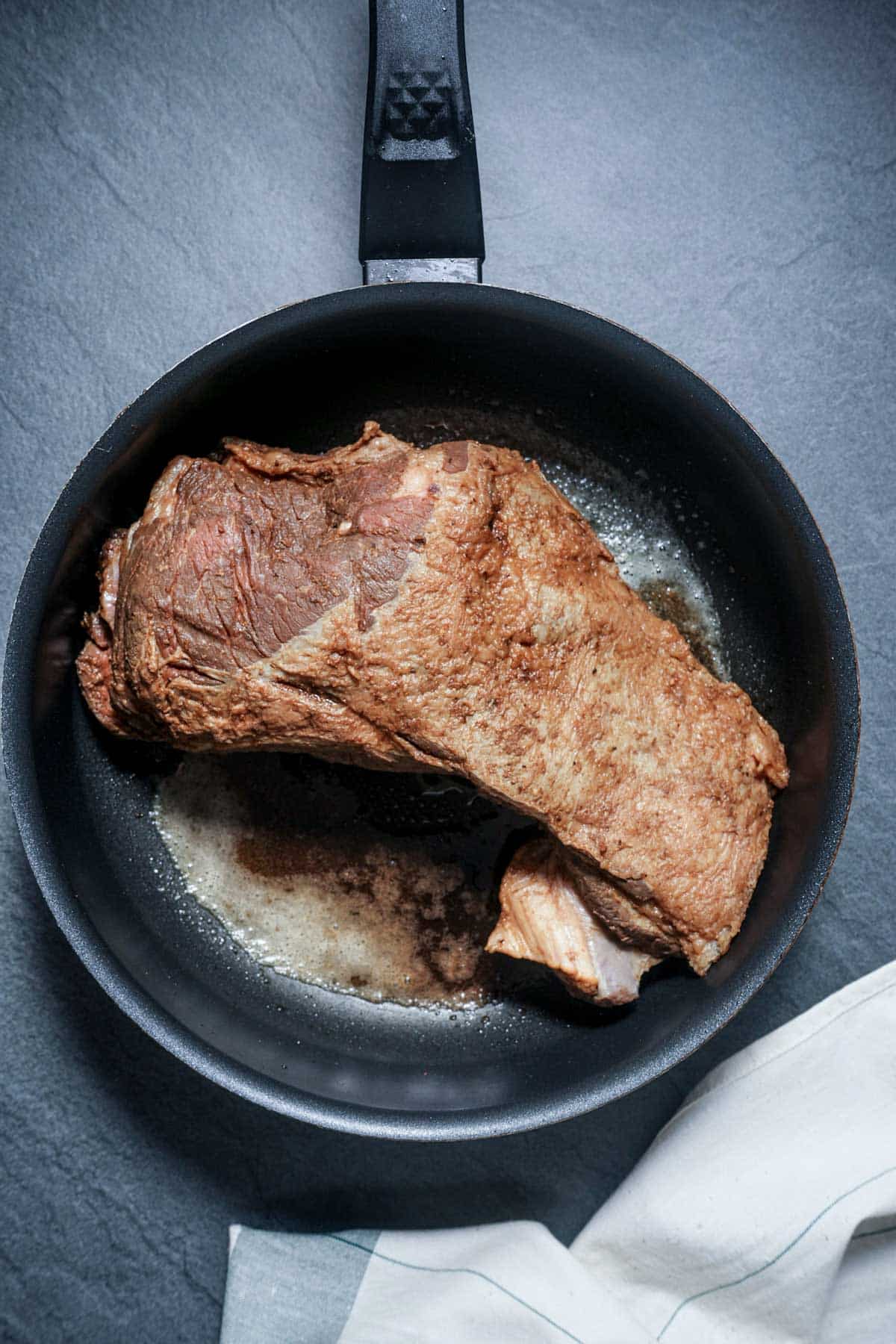 beef being seared in a skillet