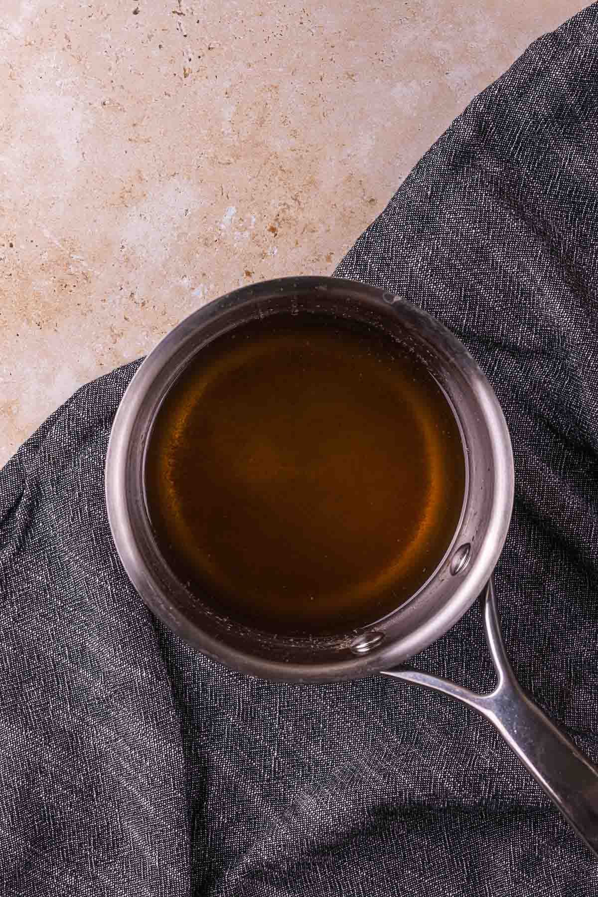 clear brown liquid in a saucepan on a blue towel