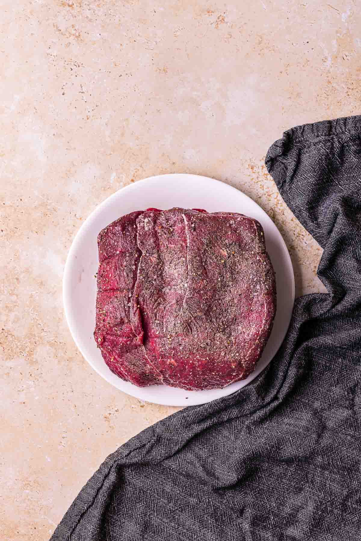 a raw beef roast seasoned with salt and pepper