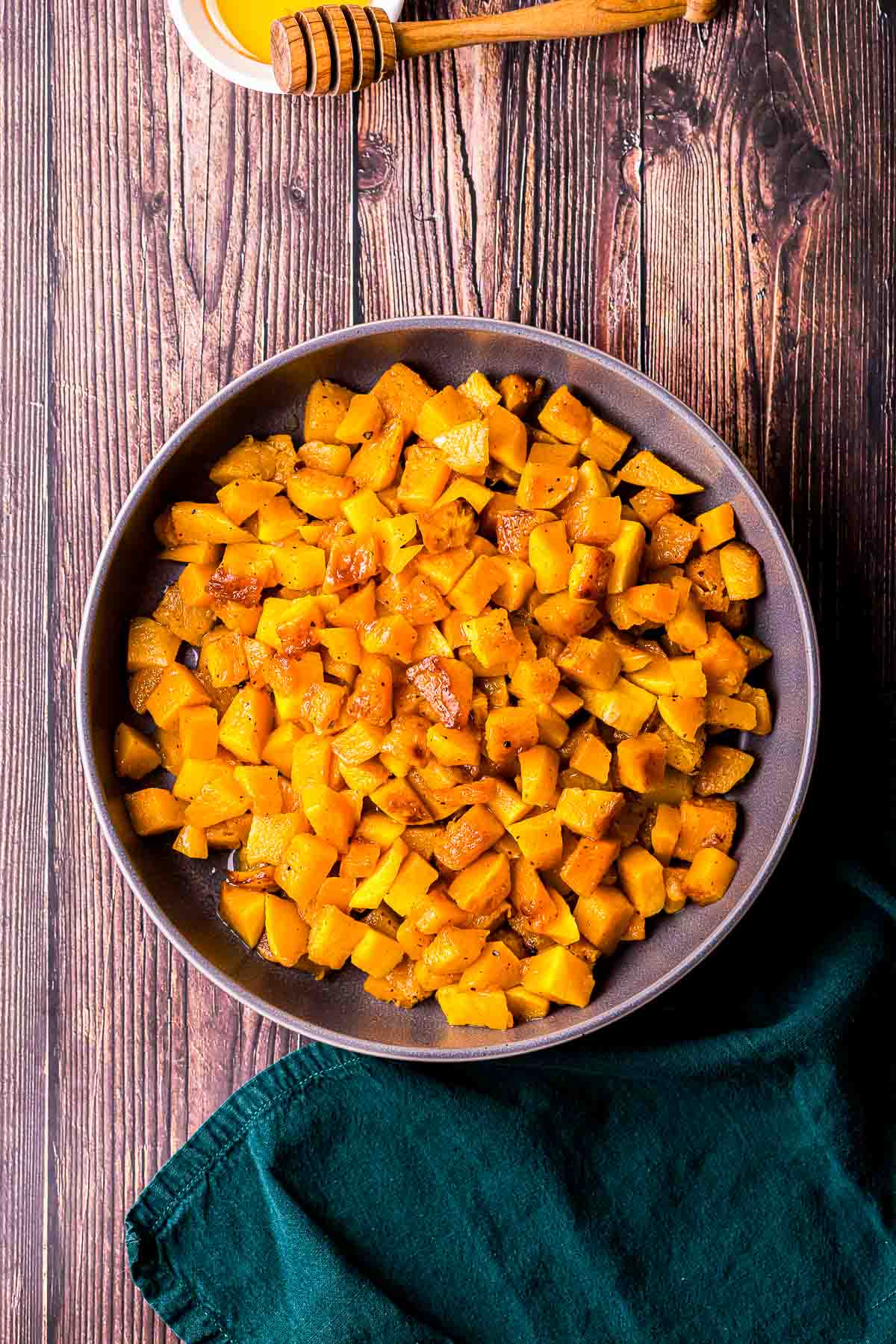a bowl of cooked pieces of butternut squash on a wood board