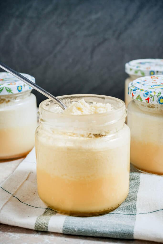 a close up view of a spoon in a jar of yellowish custard