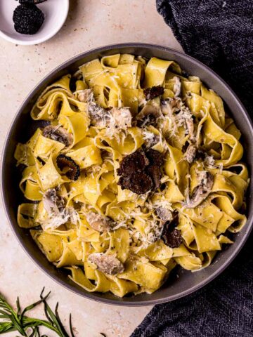 a dish of creamy pasta with black truffles shaved on tp