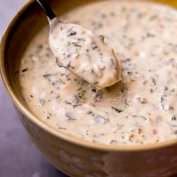 a spoon in a bowl of creamy herb sauce