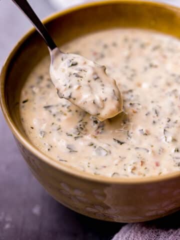 a spoon in a bowl of creamy herb sauce