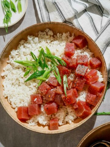 japanese marinated tuna sashimi in a bowl over rice garnished with green onions
