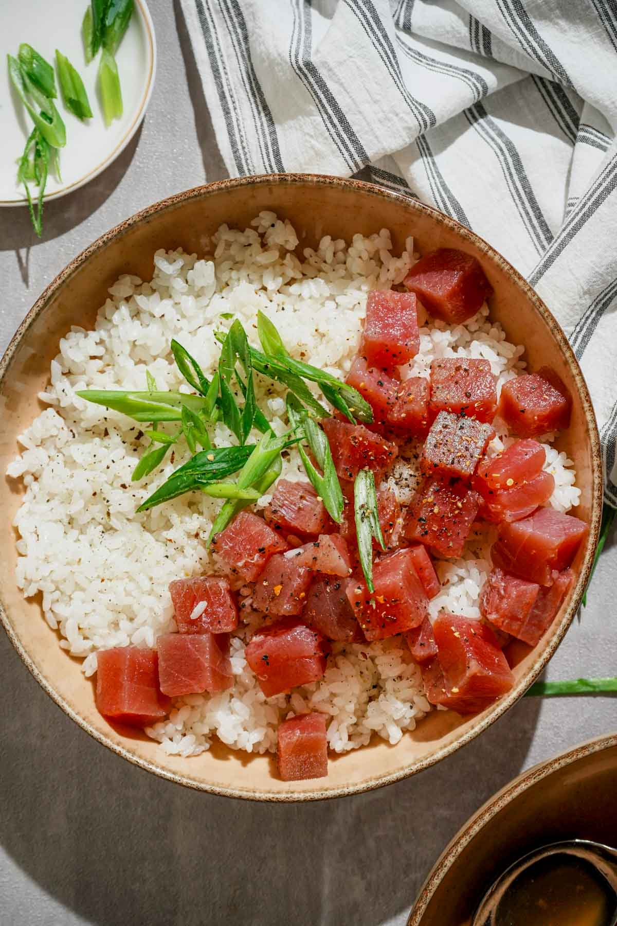 japanese marinated tuna sashimi in a bowl over rice garnished with green onions