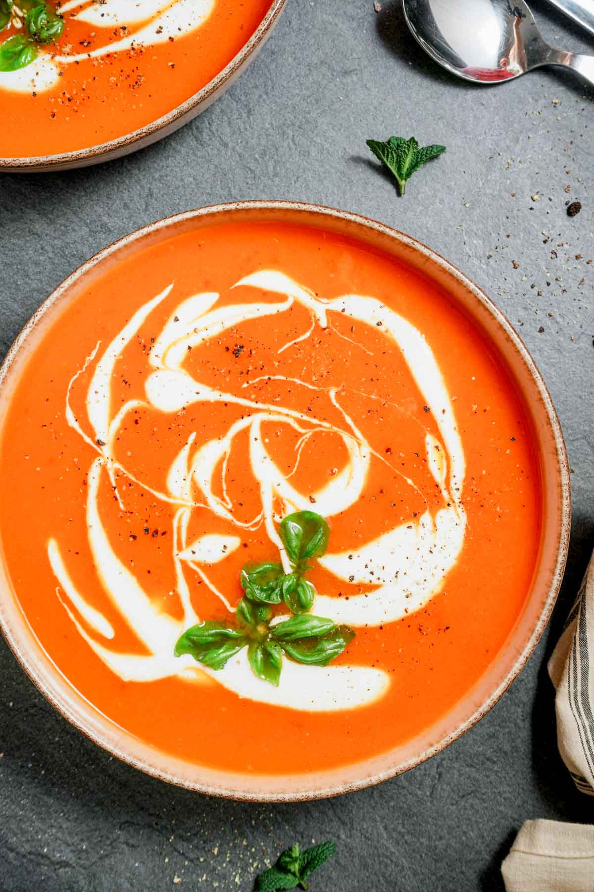 orange colored soup in a bowl with cream and herbs