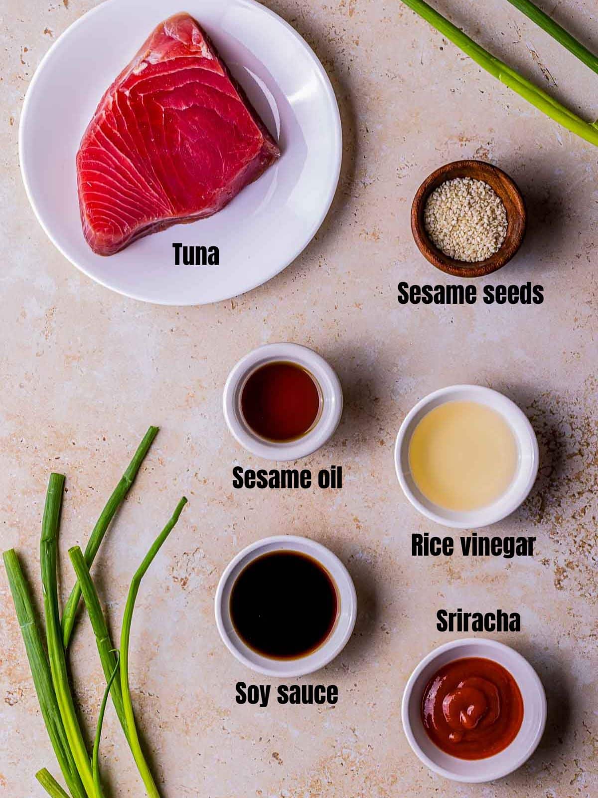 ingredients for spicy tuna on a brown board in small bowls