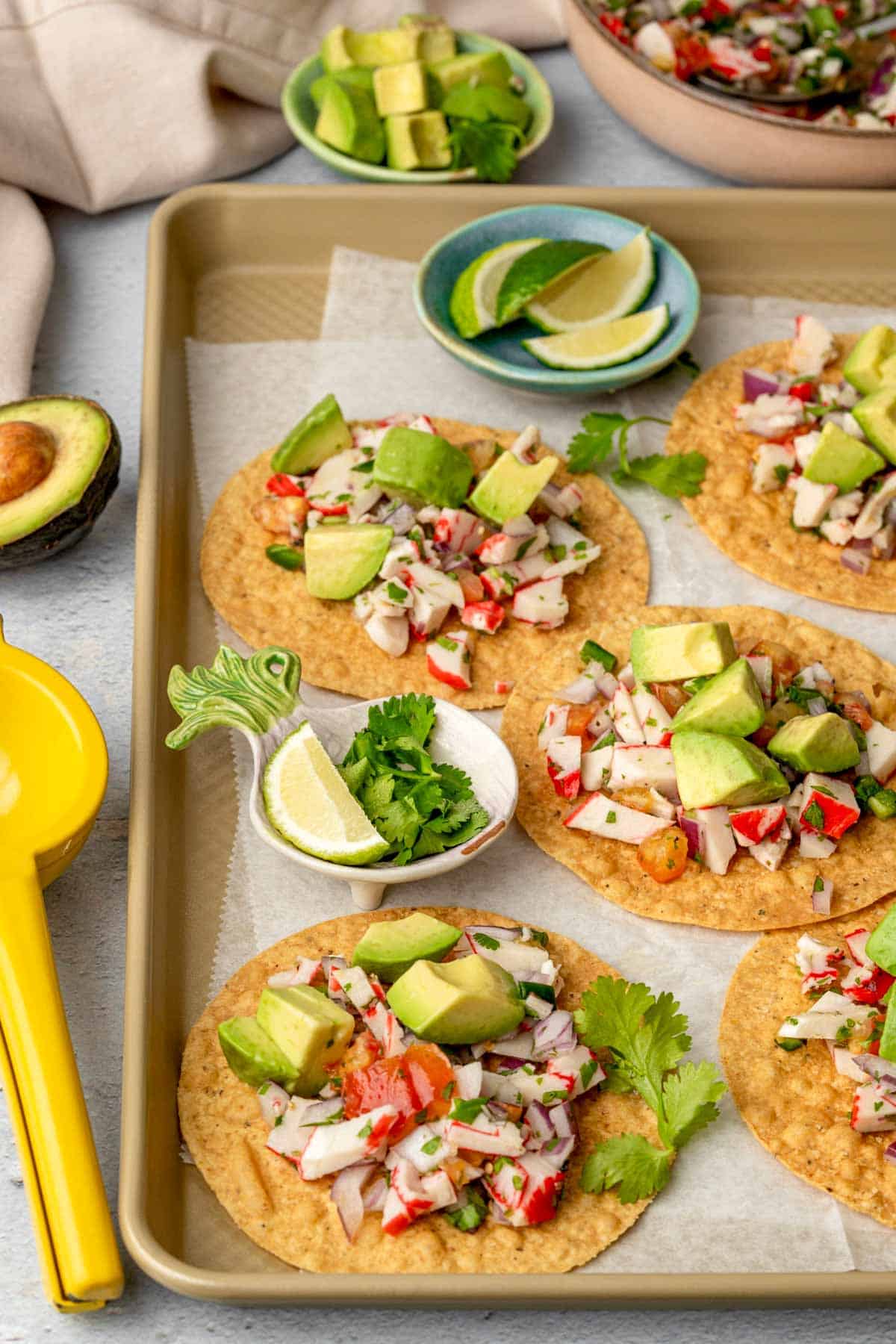 crab ceviche tostadas on a tray with avocado, lime and cilantro garnish