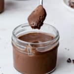 a spoon of chocolate creme being taken out of a jar