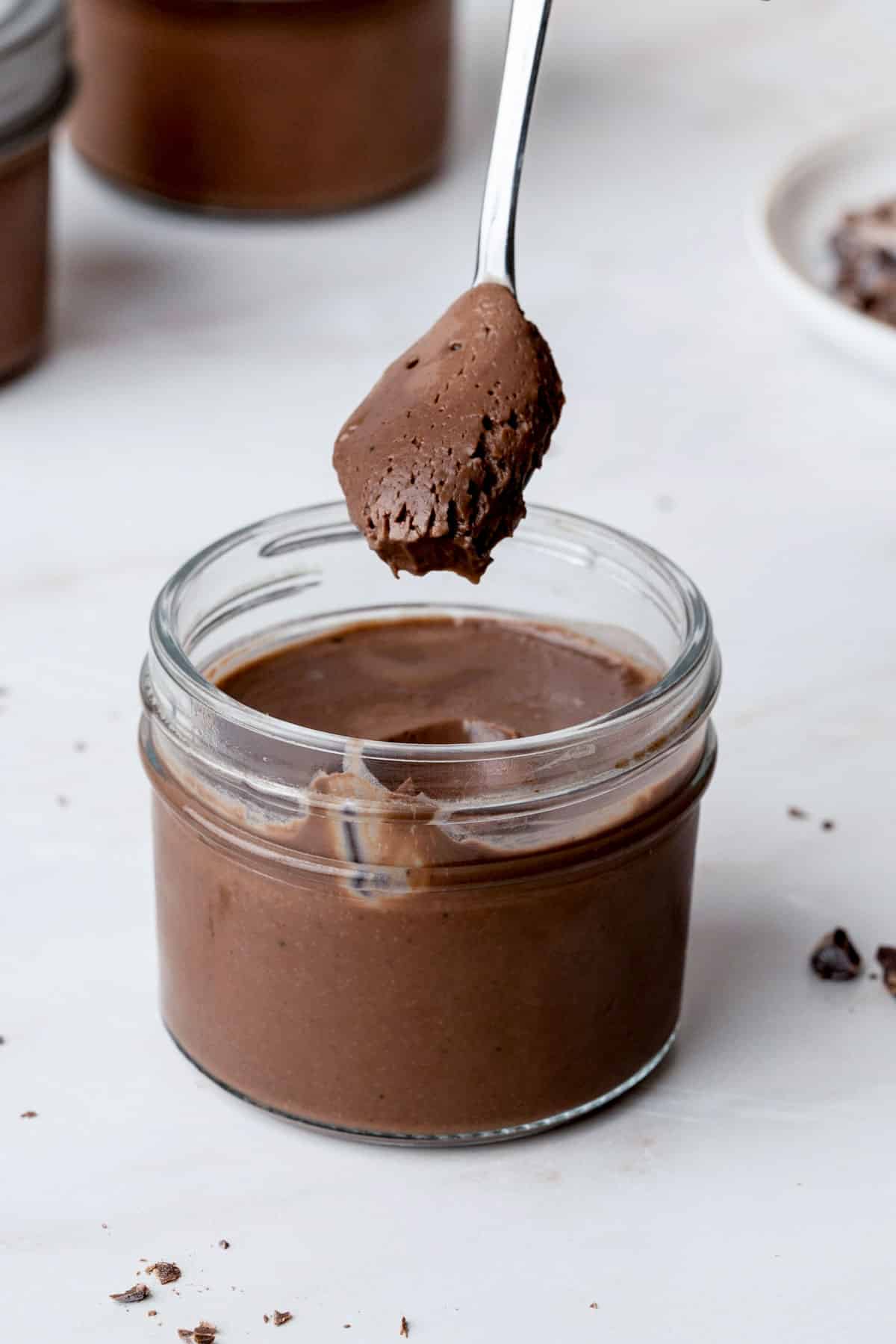 a spoon of chocolate creme being taken out of a jar