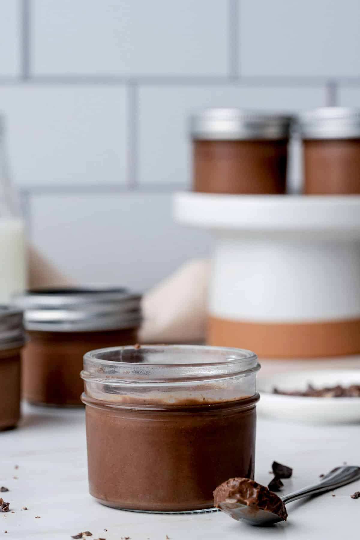 jar of chocolate cream with a spoon on the side on a white surface