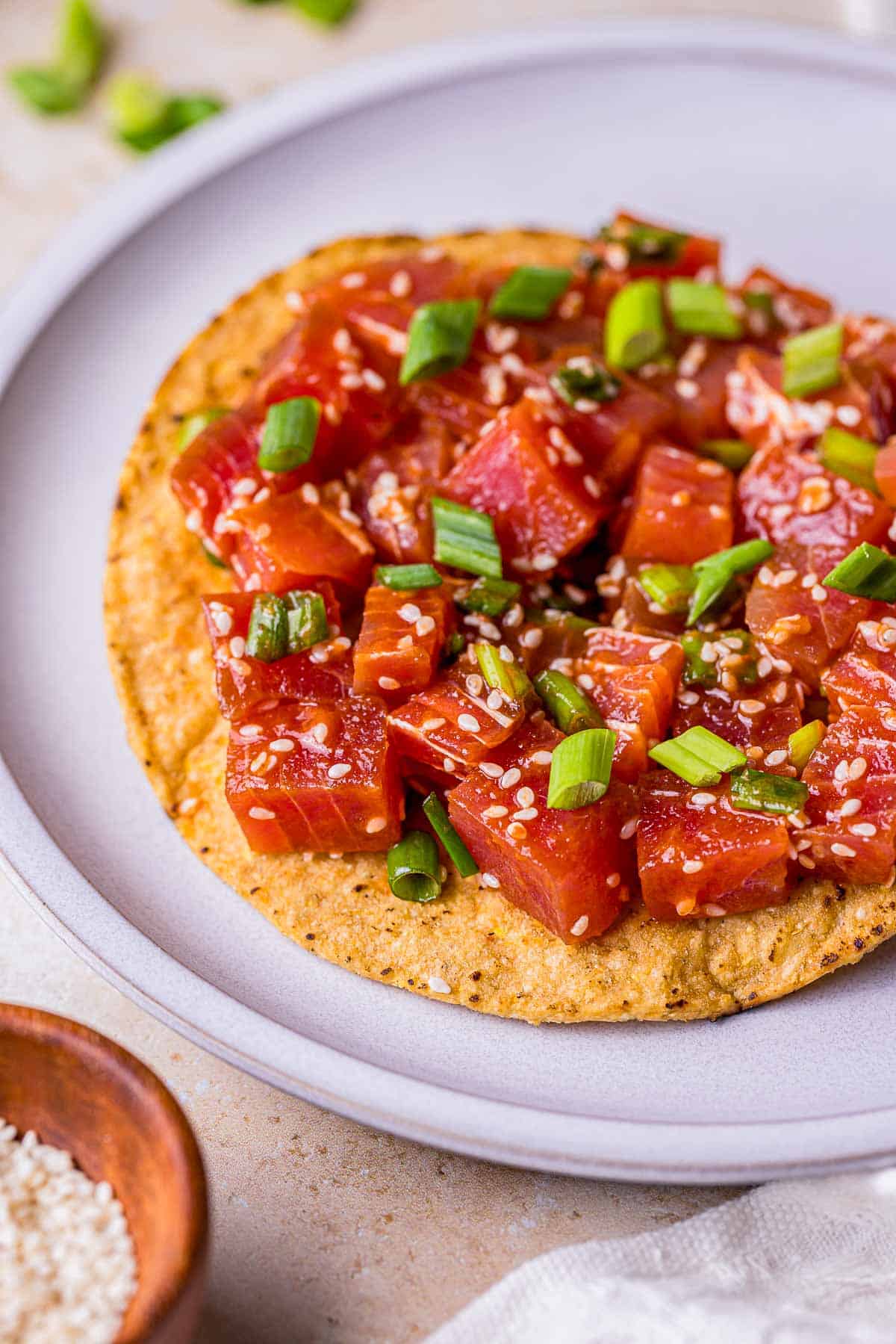 spicy tuna on a tostada with green onions and sesame seeds