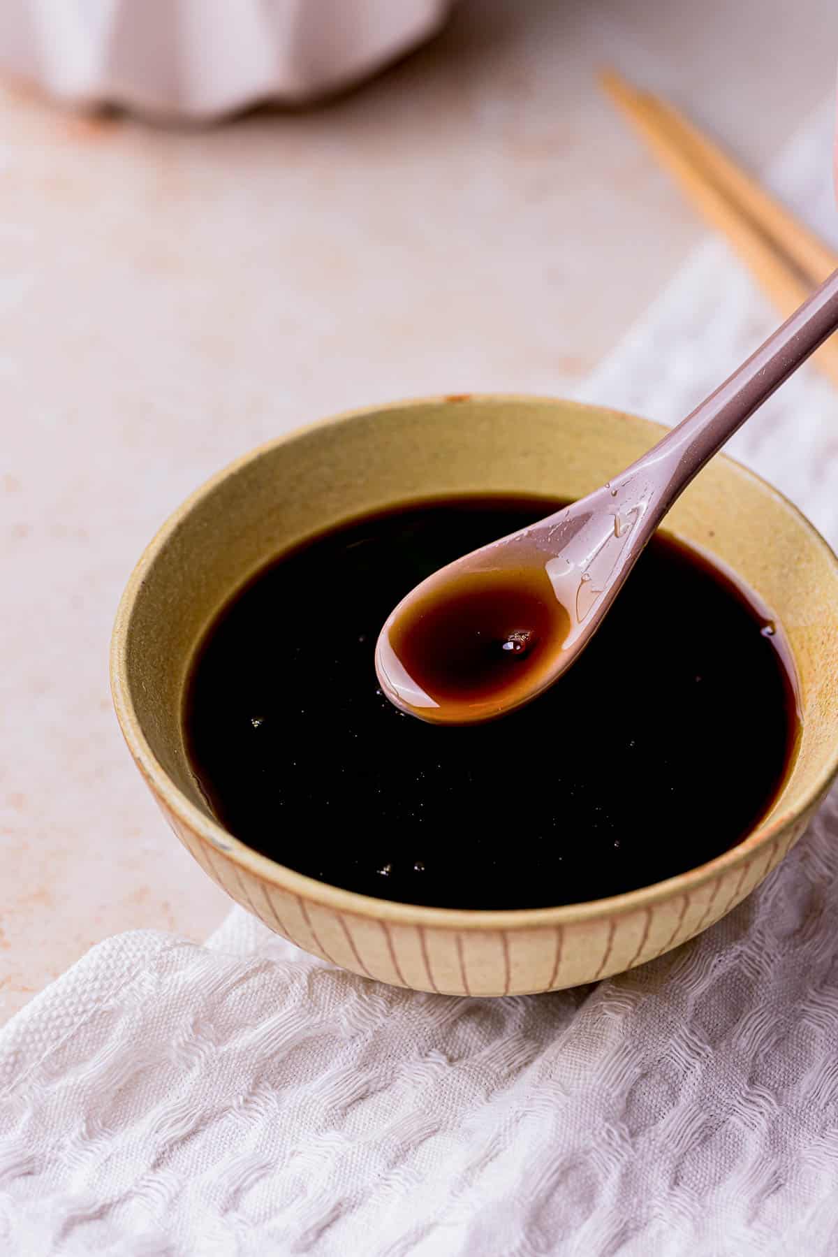 a bowl of dark brown sauce and a wooden spoon over top