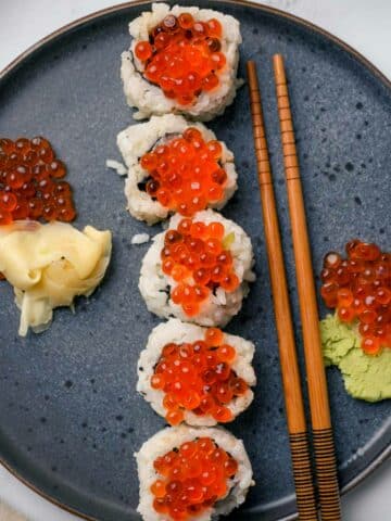 sushi rolls with orange caviar on top and ginger and wasabi on the side