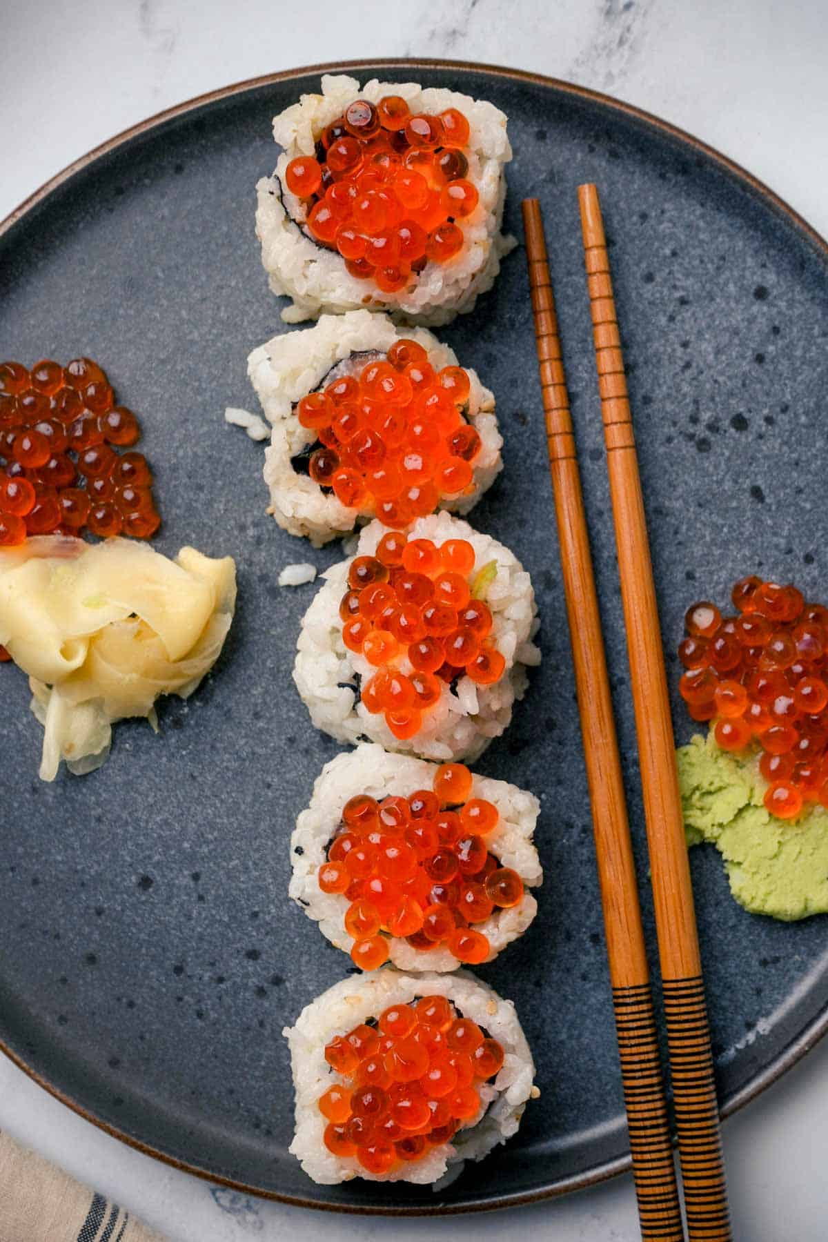 sushi rolls with orange caviar on top and ginger and wasabi on the side