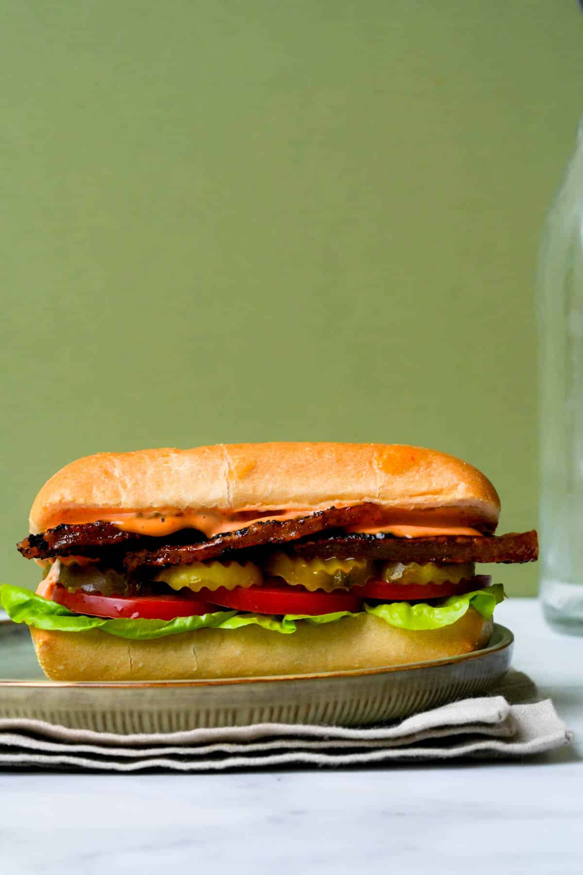 side view of a pork belly sandwich with lettuce and tomato
