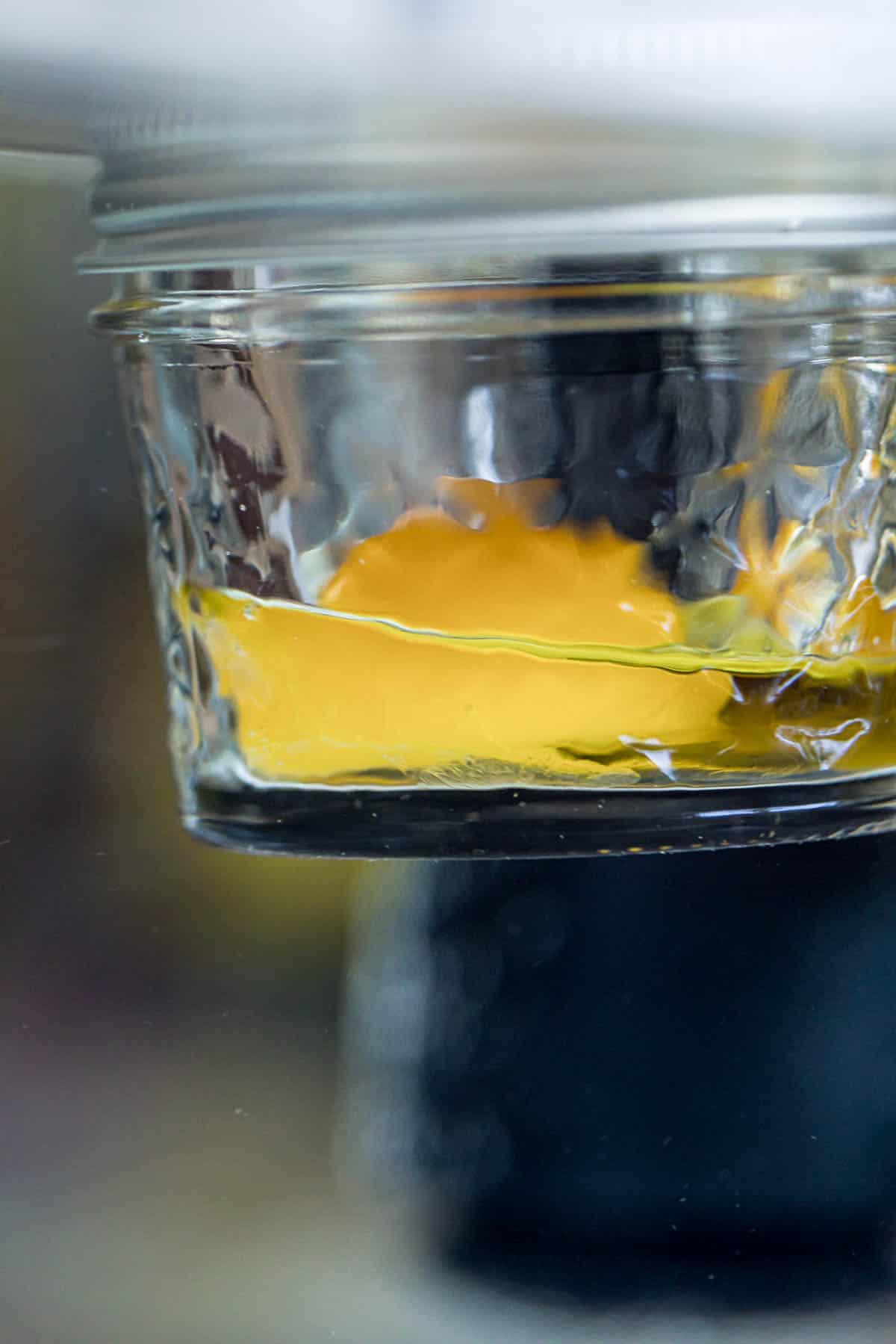 an egg yolk in a jar with olive oil cooking in a water bath