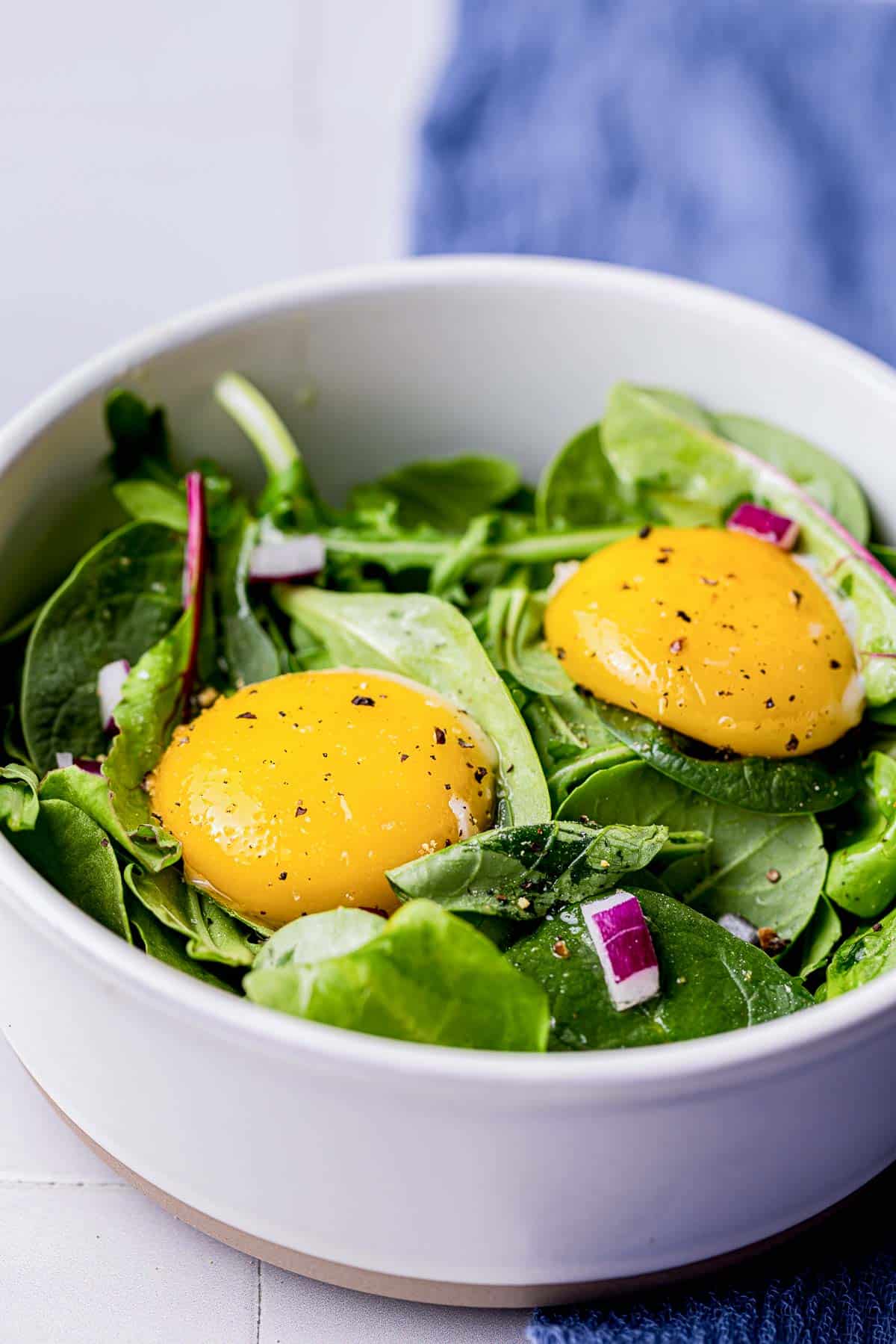 a green salad with 2 sous vide egg yolks on top