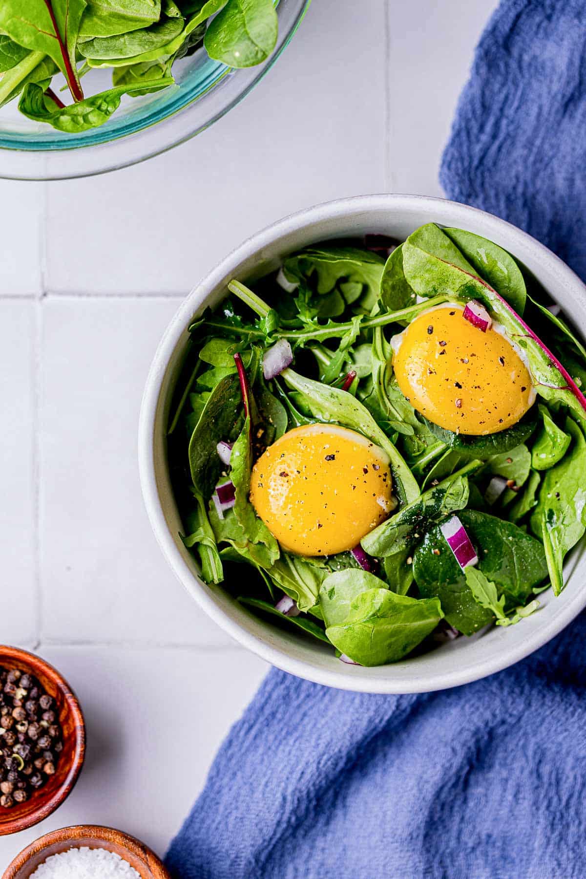 2 egg yolks over top of a green salad in a bowl