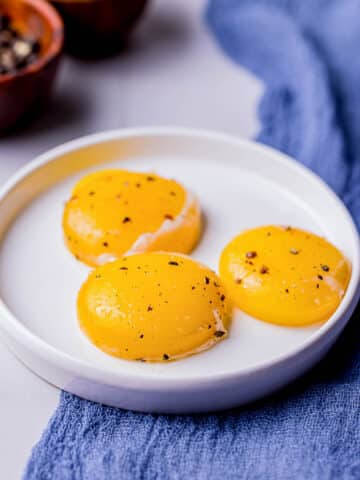 3 sous vide egg yolks on a white plate