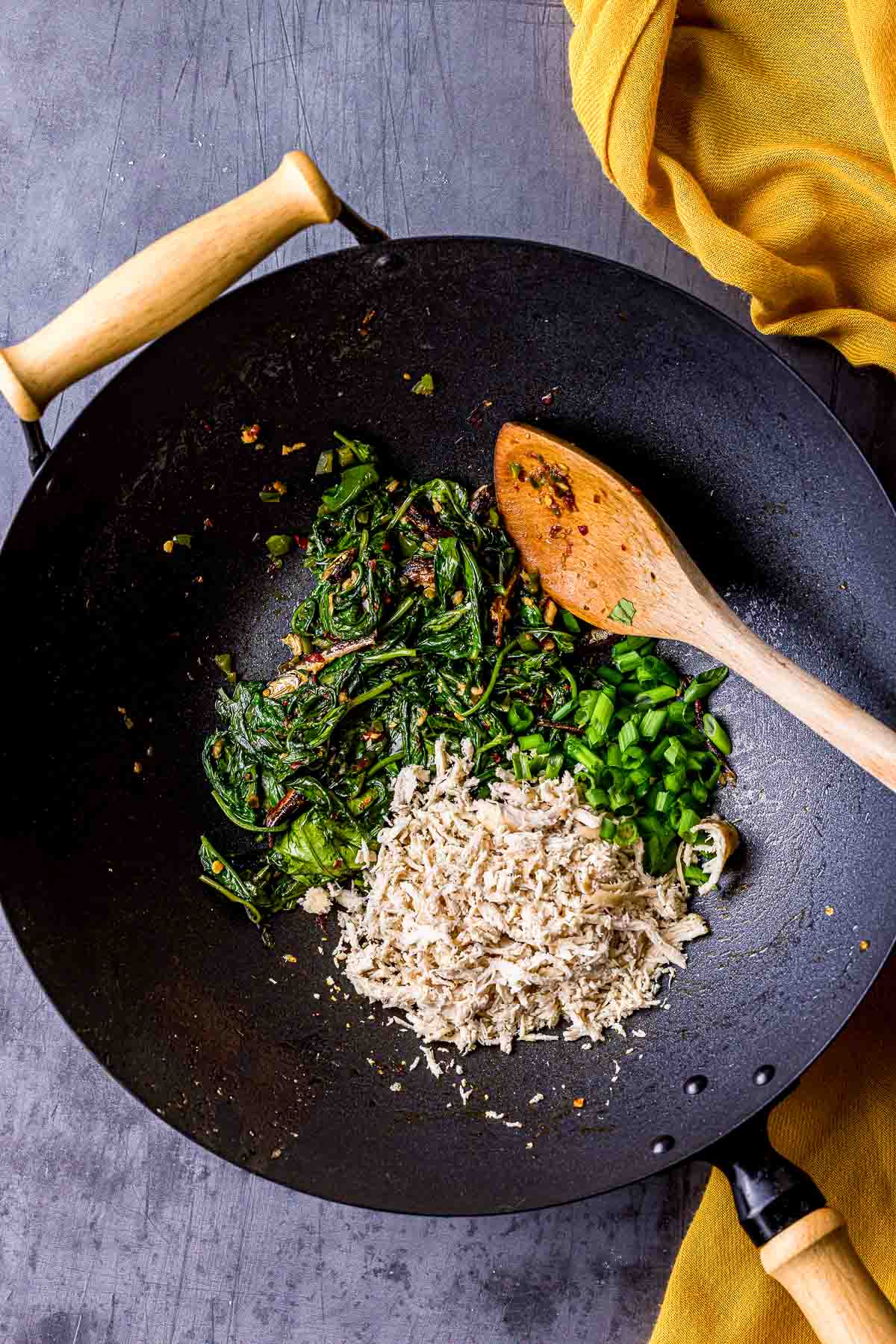 greens and shredded chicken cooking in a wok