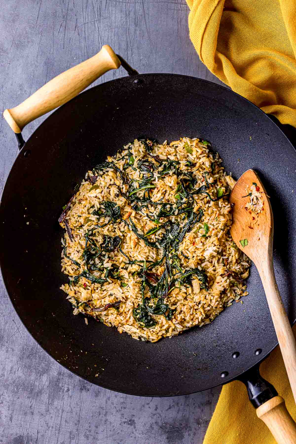 fried rice with green and a wooden spoon in a wok