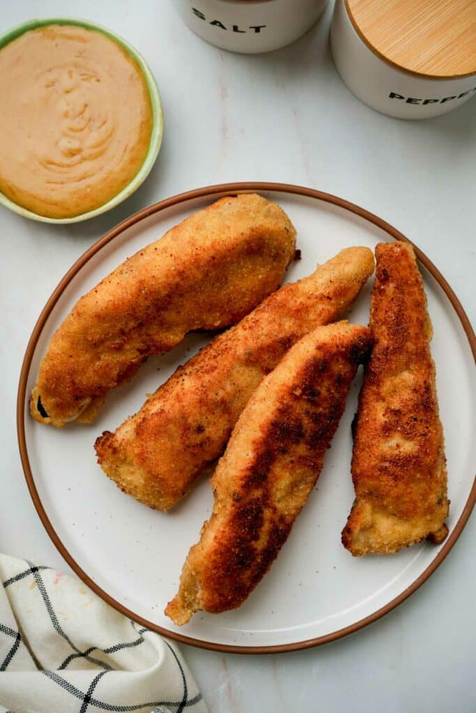 a plate of fried chicken fingers with honey mustard sauce
